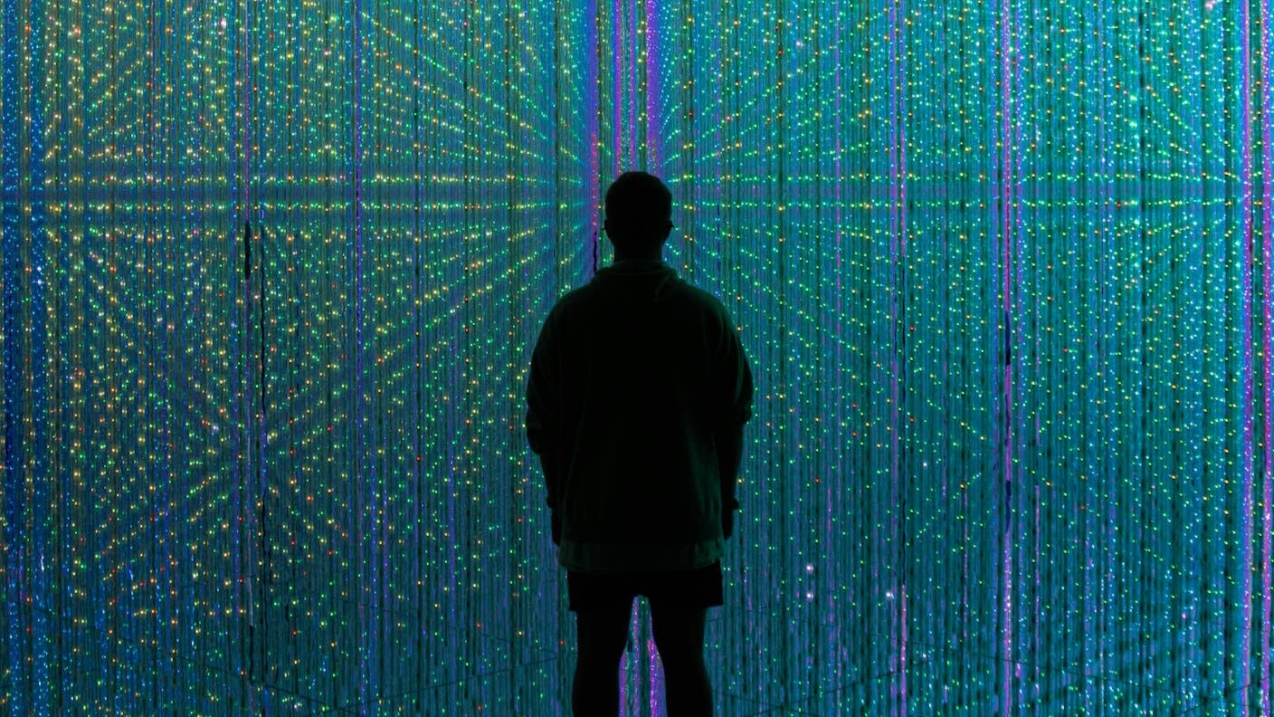 Evidence Shows AI Systems Are Already Too Much Like Humans. Will That Be a Problem? A human silhouetted in front of a curtain of LED lights.